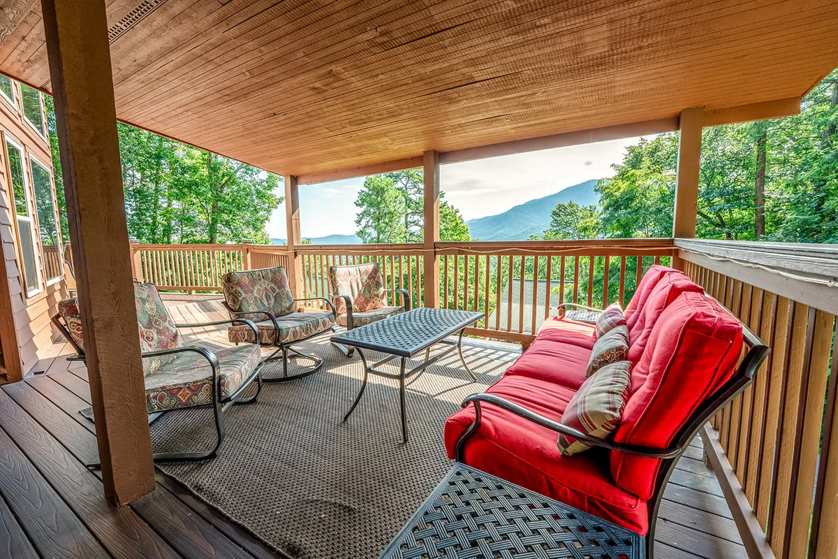 An inviting outdoor seating area with a comfortable table and chairs facing a spectacular mountain vista. The tranquil setting is ideal for socializing, enjoying meals, or soaking in the beauty of the Smoky Mountains at any time of day.